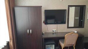 Une chambre comprenant un placard, un bureau avec une chaise, une télévision et un miroir.