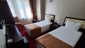 Une chambre d’hôtel avec deux lits, un bureau, une chaise, une télévision et une fenêtre avec des rideaux.