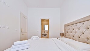 Ein Hotelzimmer mit einem Bett, einer Nachttischlampe, einer Tür und einem durch eine geöffnete Tür einsehbarer Badezimmer.