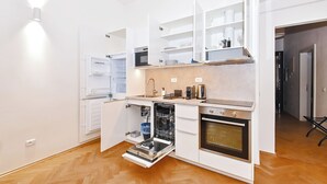 Eine moderne Küche mit weißen Schränken, einem Geschirrspüler, einem Backofen und einer eingebauten Mikrowelle.
