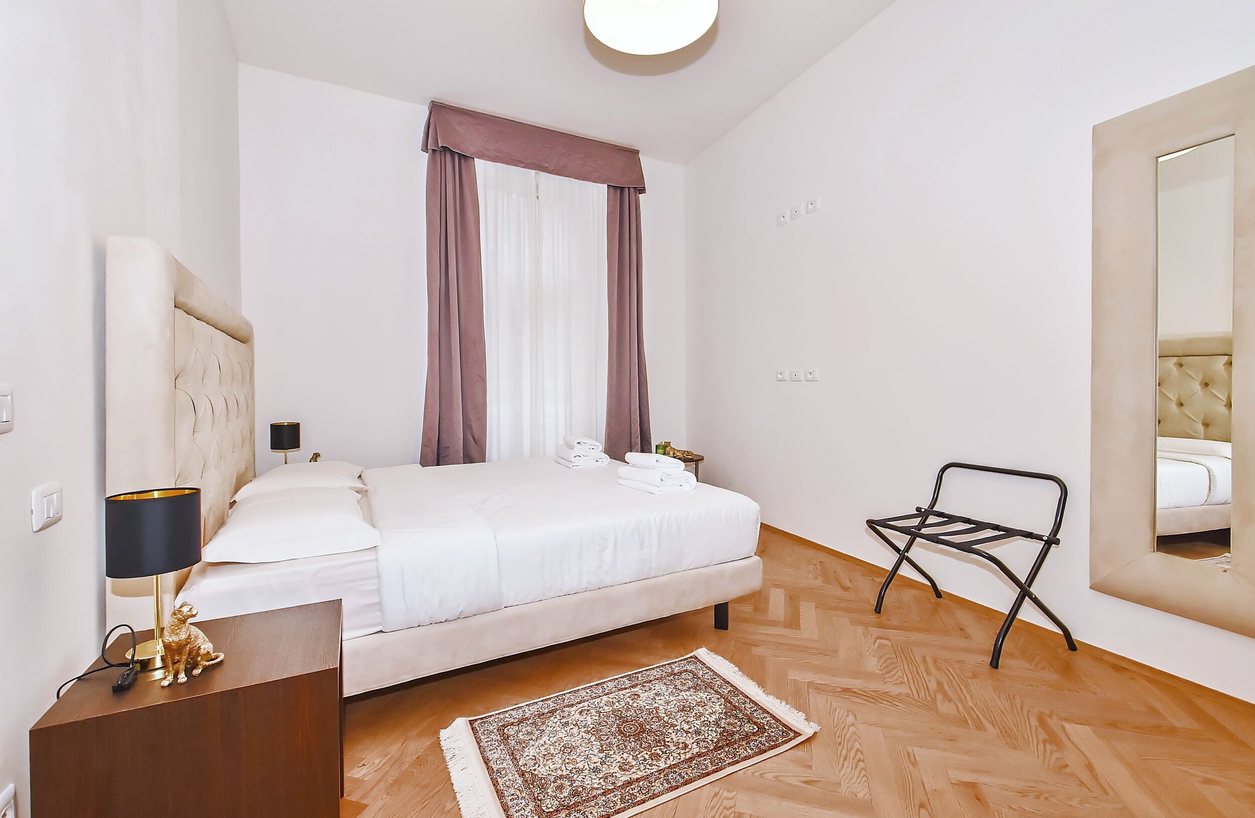 A bedroom with a bed, bedside table, lamp, and a small chair.