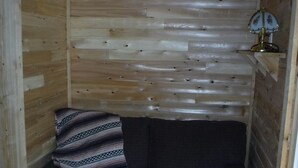 A small, cozy room with wooden walls and a dark-colored sofa. - Rustic Bunkie with Lake Front View! (Echo Bay)