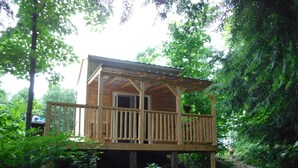 A wooden cabin with a balcony, surrounded by dense foliage. - Rustic Bunkie with Lake Front View! (Echo Bay)