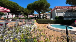 Zona de piscina amb para-sols, gandules i piscina.