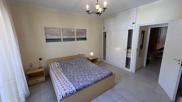 A bedroom with a bed, bedside table, lamp, wardrobe, and a ceiling light fixture.