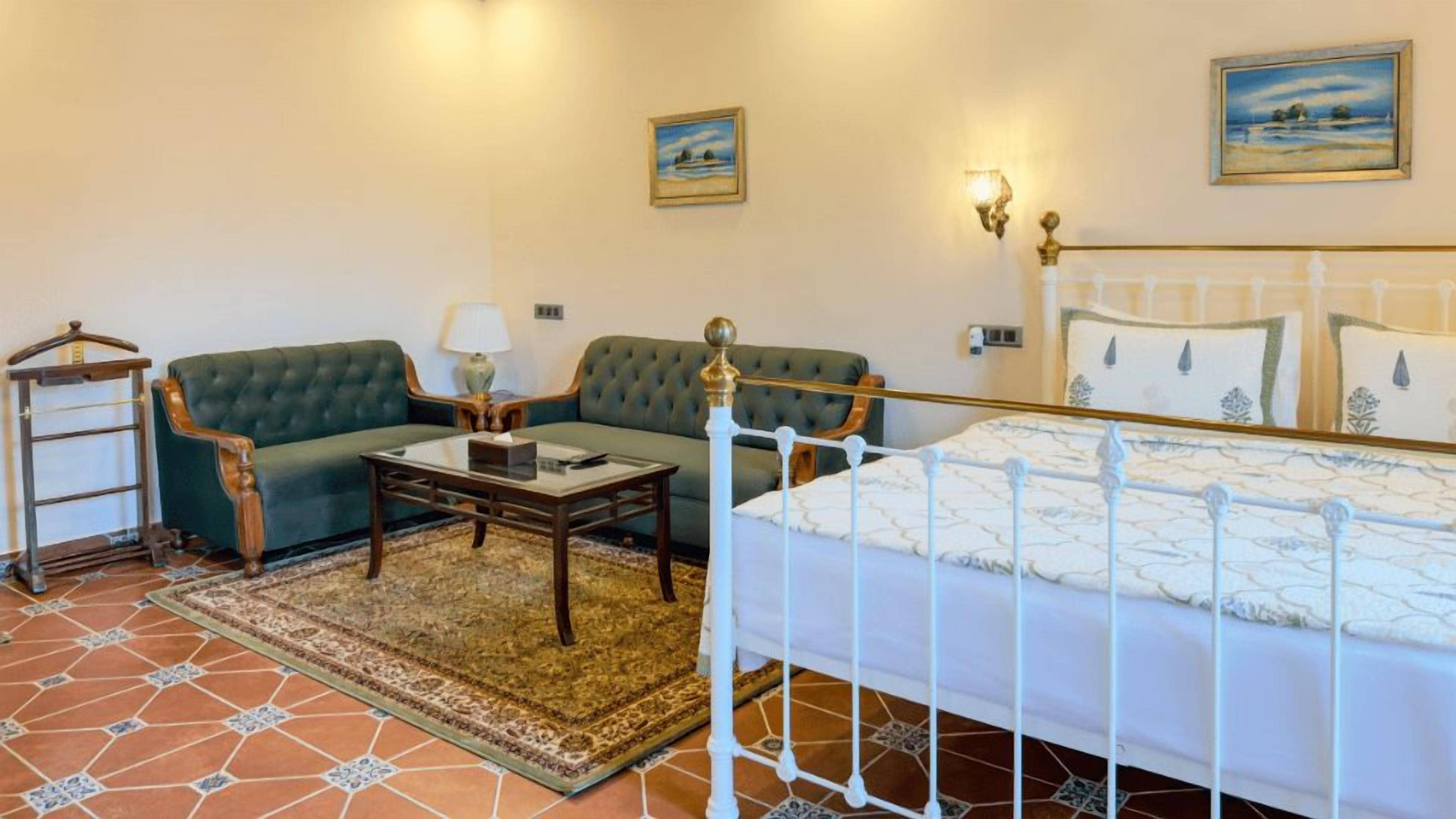 Een kamer met een bed, twee slaapbanken, een tafeltje en een lamp.