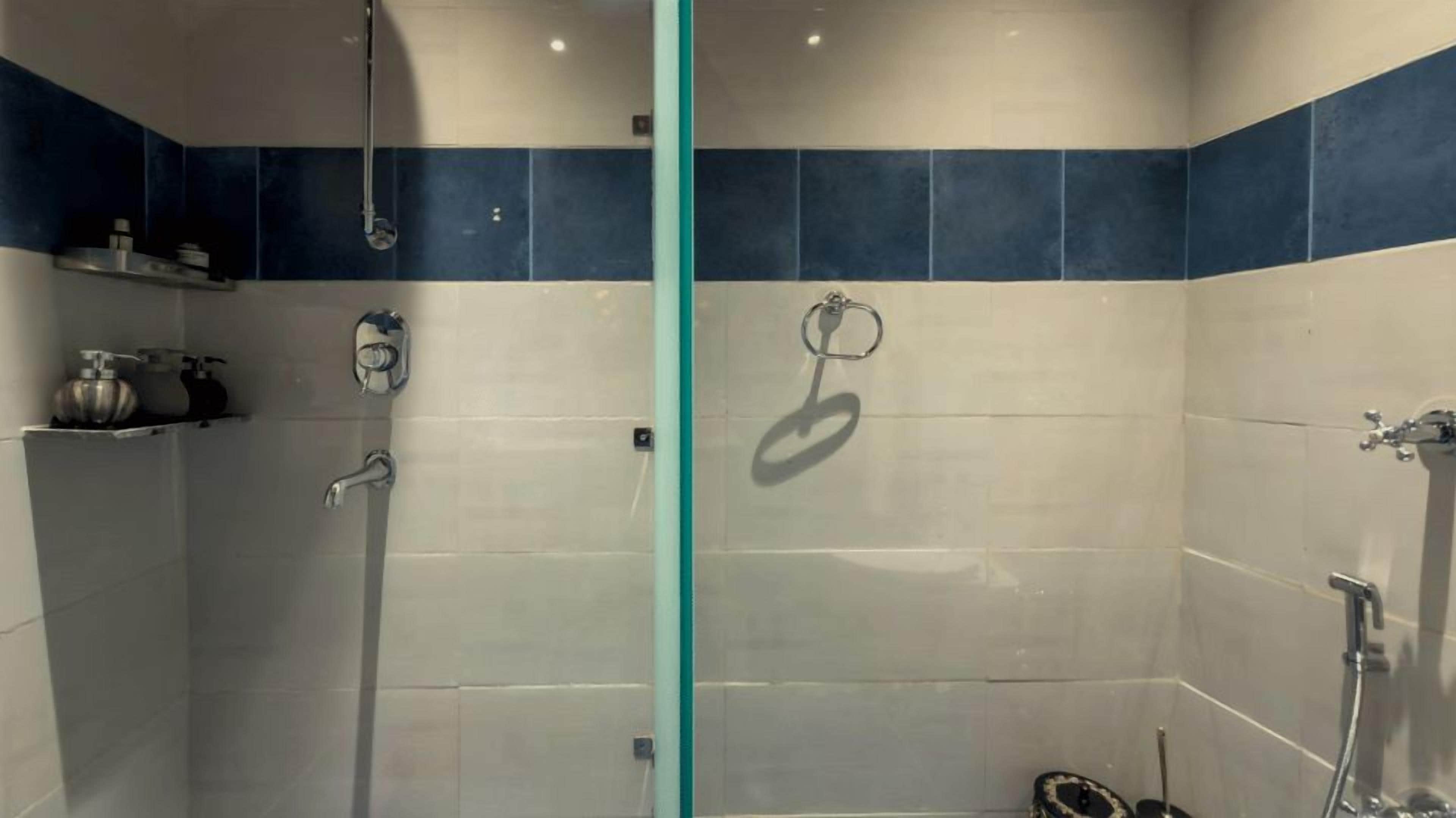 A shower with a glass partition, a towel ring, and a showerhead.