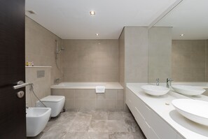 Um banheiro moderno com banheira, duas pias e um bidê.