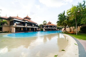 Et hotel med swimmingpool, flere balkoner og palmer.