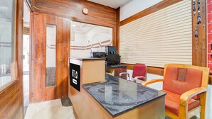 A reception desk with a computer, a clock, and a red chair. - Deluxe Olive Residency (Kottayam)