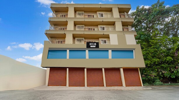 A multi-story hotel with balconies, a sign indicating it is a hotel, and closed shutters on the ground floor. - Deluxe Olive Residency (Kottayam)