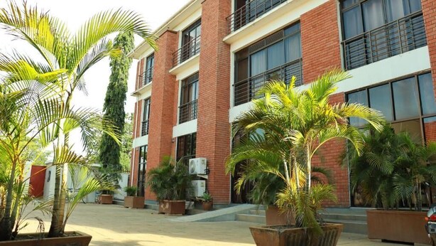 A multi-story building with brick exterior, large windows, and potted plants in the courtyard.