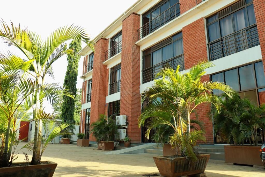 Un edificio con fachada de ladrillo, ventanas amplias y plantas en macetas en el patio.