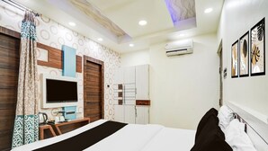 A hotel room with a bed, a TV, a wardrobe, and a desk with a chair. - Classic With Balconyarjun International (Lucknow)