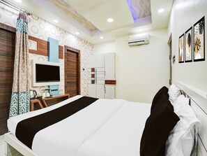 Ein Hotelzimmer mit Bett, Fernseher, Kleiderschrank und Schreibtisch mit Stuhl.