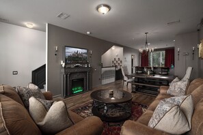 A spacious living room with a fireplace, a dining area with a chandelier, and a large window with a view. - Secret Wizard HQ: Immersive Magical Stay Near Epic (Orlando)