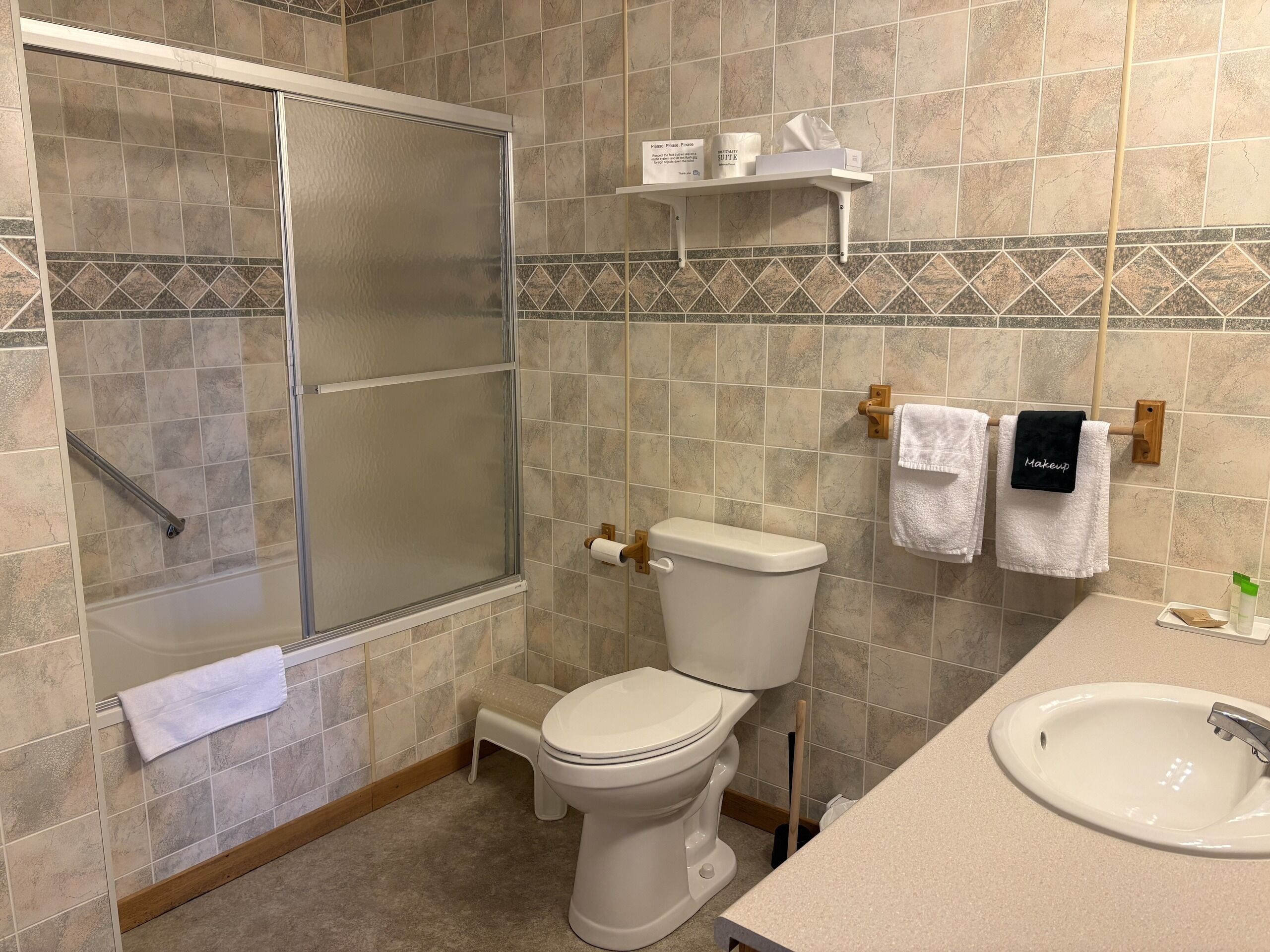 Un baño con ducha, inodoro, lavabo y toallero.