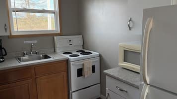Una cocina equipada con estufa, fregadero, refrigerador y microondas.