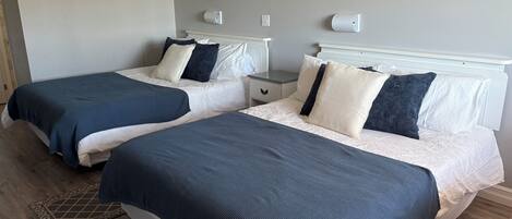 Two twin beds with matching headboards, a bedside table, a nightstand, and a wall-mounted light fixture.