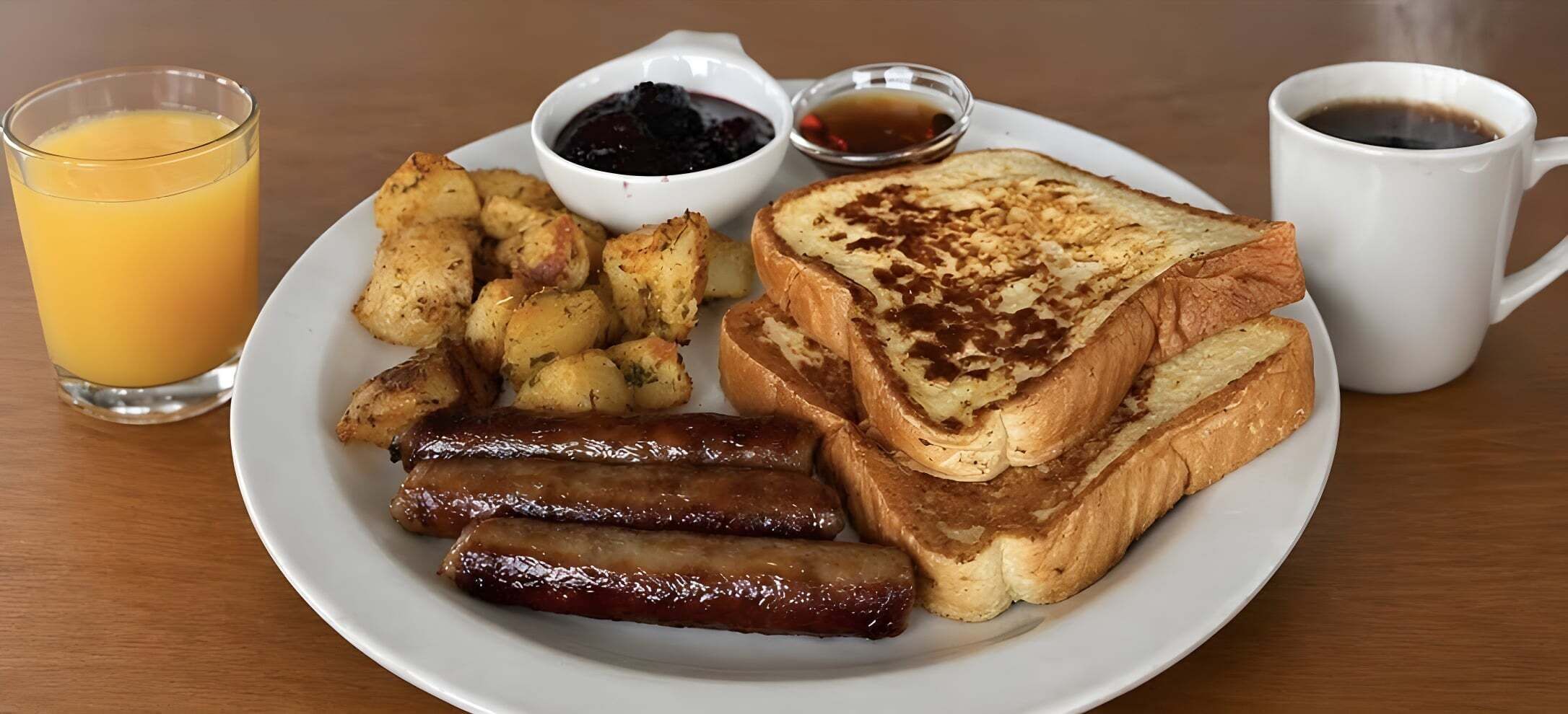 A breakfast plate with toast, sausages, potatoes, and a glass of orange juice.