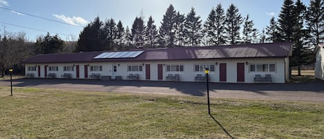 A motel with a red roof, multiple windows, and a parking area.