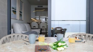 Ein moderner Essbereich mit einem Marmortisch, zwei Stühlen, einem Buch, einem Blumenstrauß und zwei Gläsern Orangensaft.