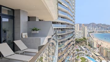 A high-rise hotel with balconies, a pool, and a beach view.