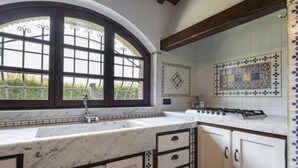 A kitchen with a large window, white cabinets, and a tiled backsplash. - Villa del Rio by MMega (Strettoia)