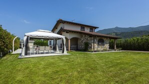 A house with a stone facade, a covered patio, and a well-maintained lawn. - Villa del Rio by MMega (Strettoia)