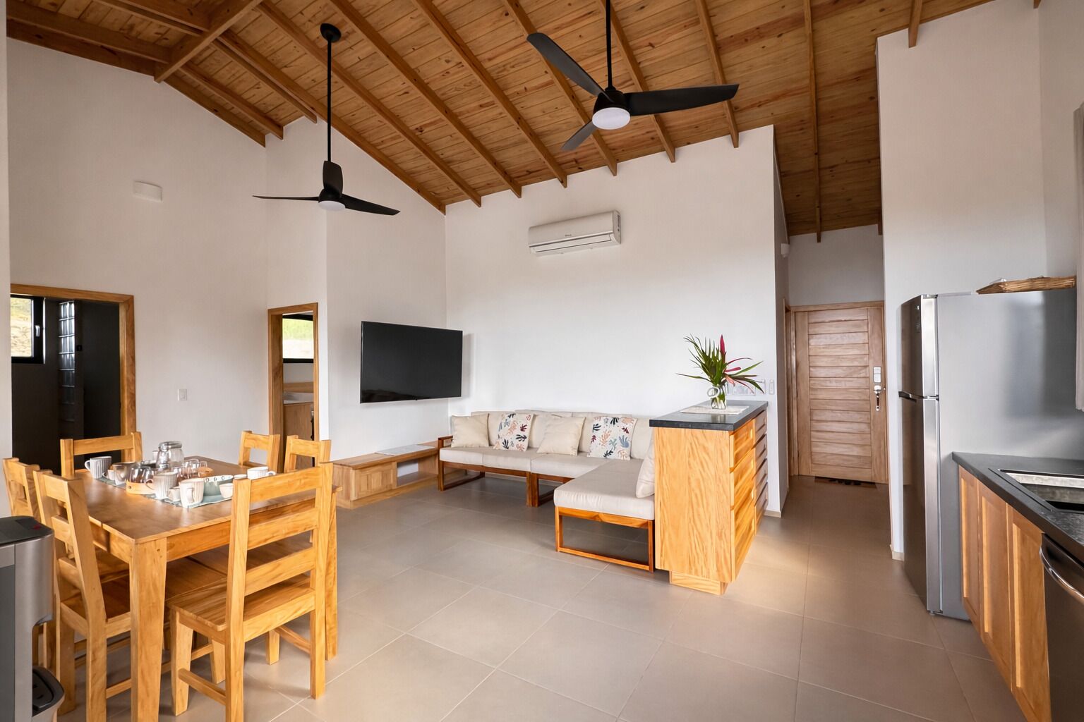 A modern kitchen with wooden cabinets, a built-in refrigerator, and a dining area with a wooden table and chairs.