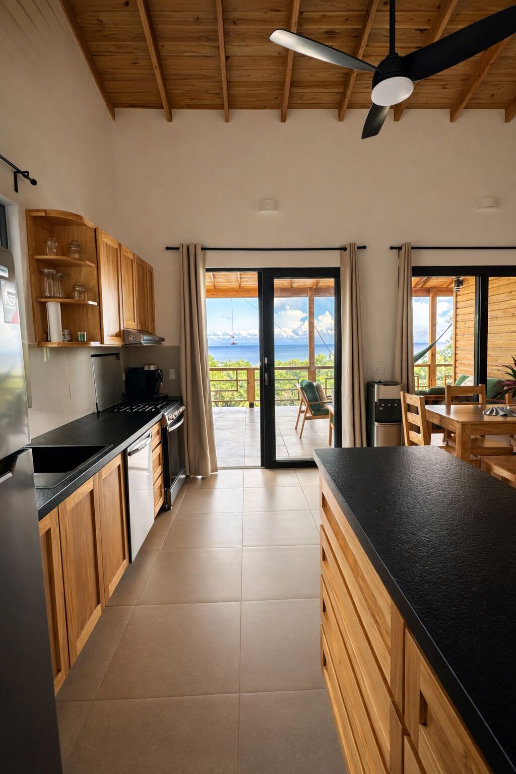 Una cocina moderna con armarios de madera, encimera negra y vistas a un espacio exterior con mesa y sillas.