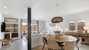 A modern living room with a sofa, dining table, chairs, and a television.
