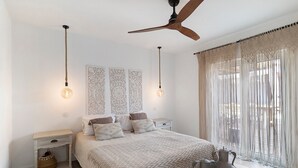 A bedroom with a bed, bedside tables, a ceiling fan, and decorative wall art.