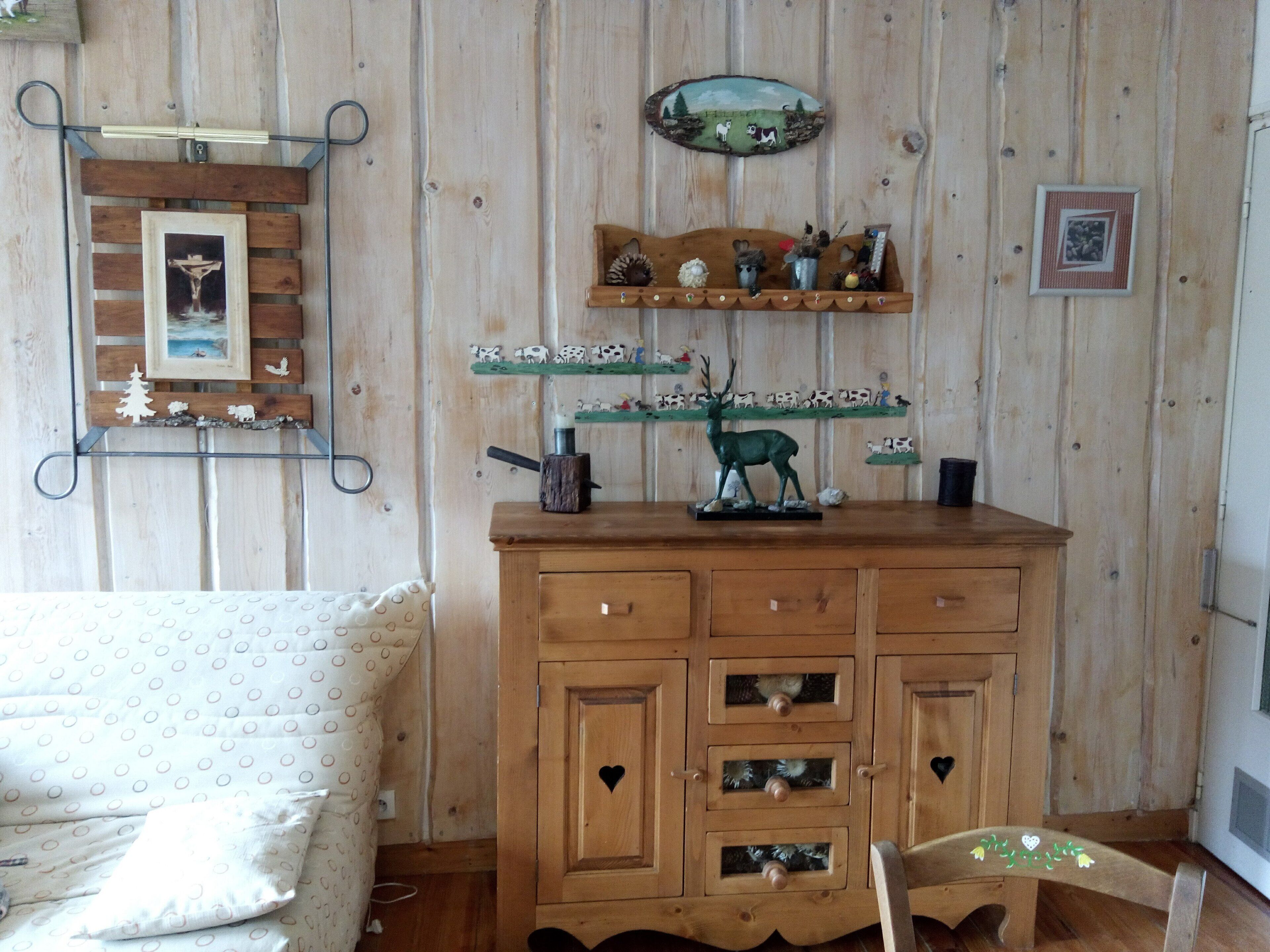 Un mueble de madera con varios cajones, una repisa con figuritas y un cuadro colgado en la pared.