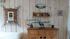 A wooden cabinet with multiple drawers, a shelf with figurines, and a wall-mounted picture frame. - STOP: My spacious two-bedroom apartment across from Écrins Park (Orcières)