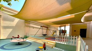 A children's play area with a swing set, a merry-go-round, and a small tricycle. - Palm Jumeirah 2BR Prime Burj Al Arab Balcony (Dubai)