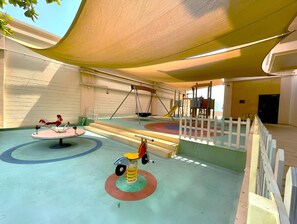 Ein Kinderspielplatz mit Schaukel, Karussell und einem kleinen Dreirad.