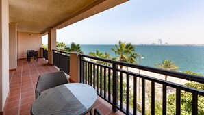 A balcony with a view of the sea, a table, and chairs. - Palm Jumeirah 2BR Prime Burj Al Arab Balcony (Dubai)