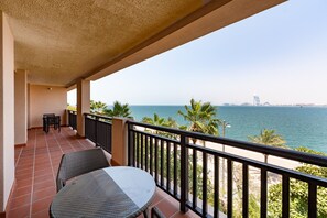 Ein Balkon mit Meerblick, einem Tisch und Stühlen.