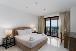 Ein Hotelzimmer mit Bett, zwei Nachttischen mit Lampen, einem Schreibtisch und einem Balkon mit Blick.