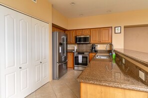 A kitchen with white cabinets, stainless steel appliances, a granite countertop, and a sink. - Alii Cove II-4 | Monthly Rental in Kona | 30-Day Stay Alii Drive (Kailua Kona)