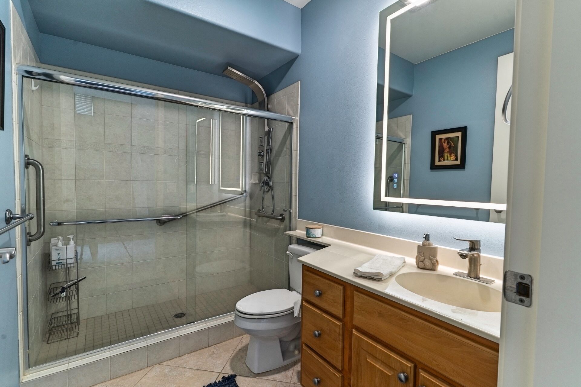 Une salle de bain avec une douche à parois de verre, des toilettes, un lavabo avec un miroir et des meubles en bois.