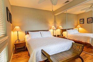 A hotel room with two beds, bedside lamps, a wooden bench, and a ceiling fan. - Alii Cove II-4 | Monthly Rental in Kona | 30-Day Stay Alii Drive (Kailua Kona)
