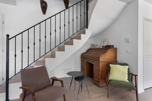 A staircase with a black railing, a wooden bench, a small round table, and a green cushioned chair. - Villa 'Maison Mennoise' with Swimming Pool (Tourrettes)