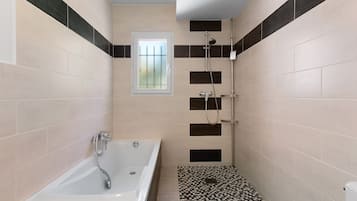 A bathroom with a bathtub, shower, and a small window.
