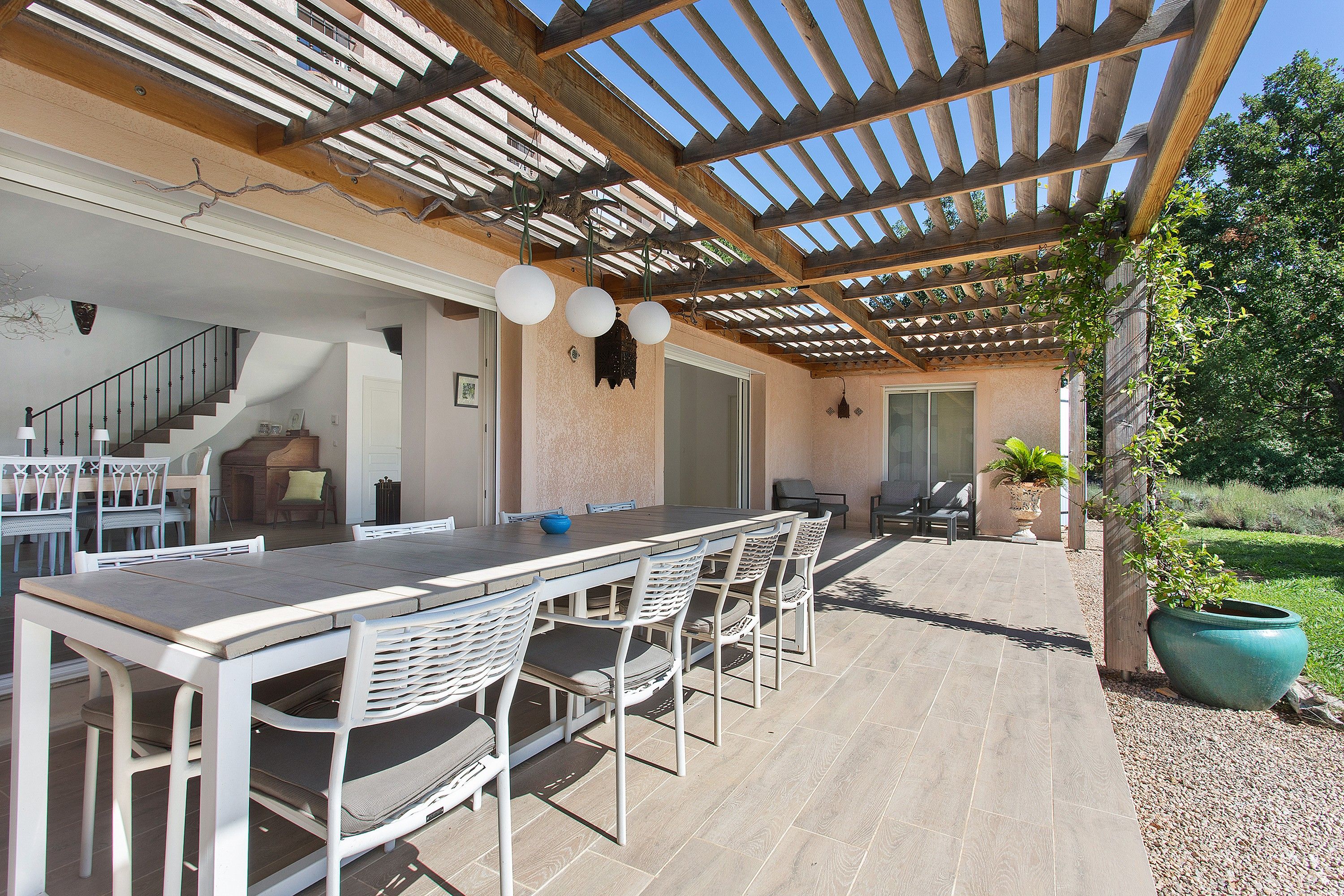 An outdoor patio with a pergola, a dining table with chairs, and a seating area with a fire pit.
