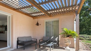 Un patio exterior con pérgola, zona de estar y una planta en maceta.
