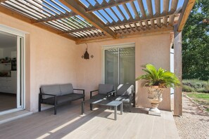 Eine Außenpatio mit einer Pergola, einer Sitzgelegenheit und einem Blumentopf.