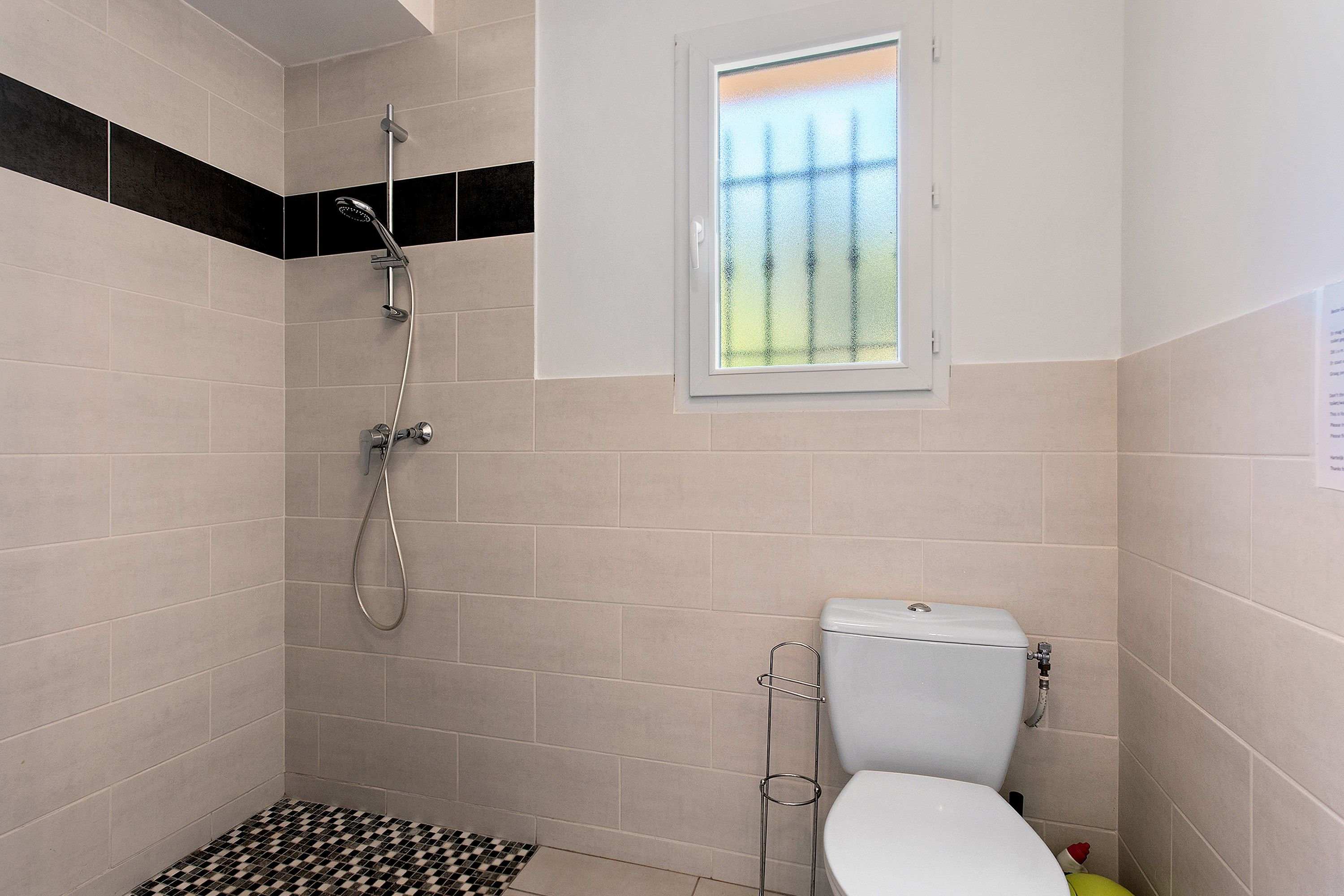 Un baño pequeño con ducha, inodoro y ventana.