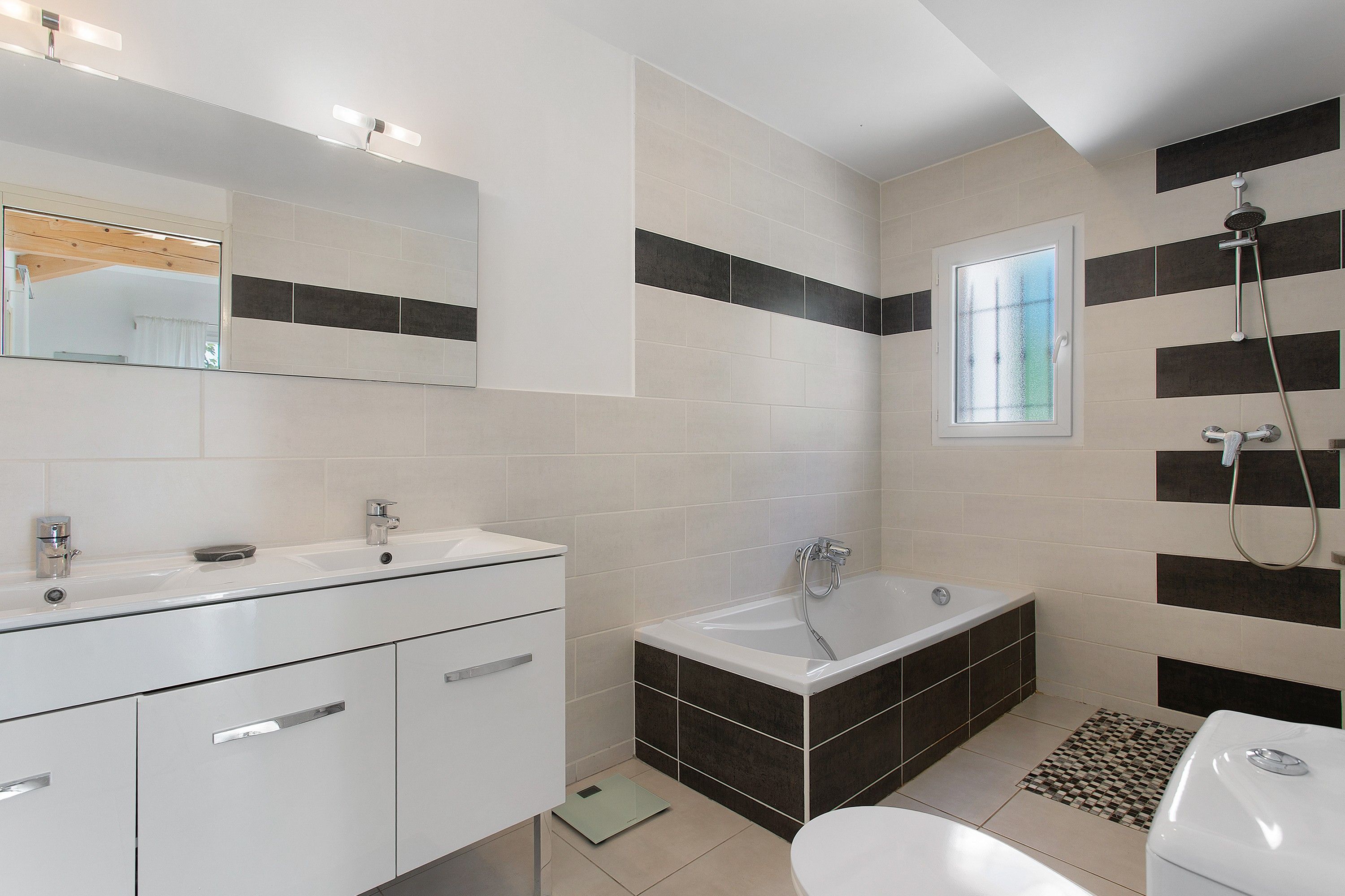 A modern bathroom with a white vanity, a bathtub, and a shower area.